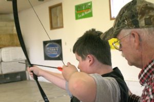 Archer Don Newell helps a visually impaired child shoot an arrow at a balloon Wednesday, at the Chinook Archer's range in Camas.