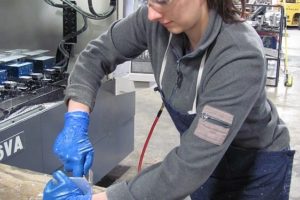 Denise Fretwell, a machinist at Micro Machining LLC, finishes parts that will be machine-dated with the month and year they were manufactured.  The company, which makes precision metal parts such as shafts, spindles, handles and nuts, is located in Building 4 in the Port of Camas-Washougal Industrial Park.