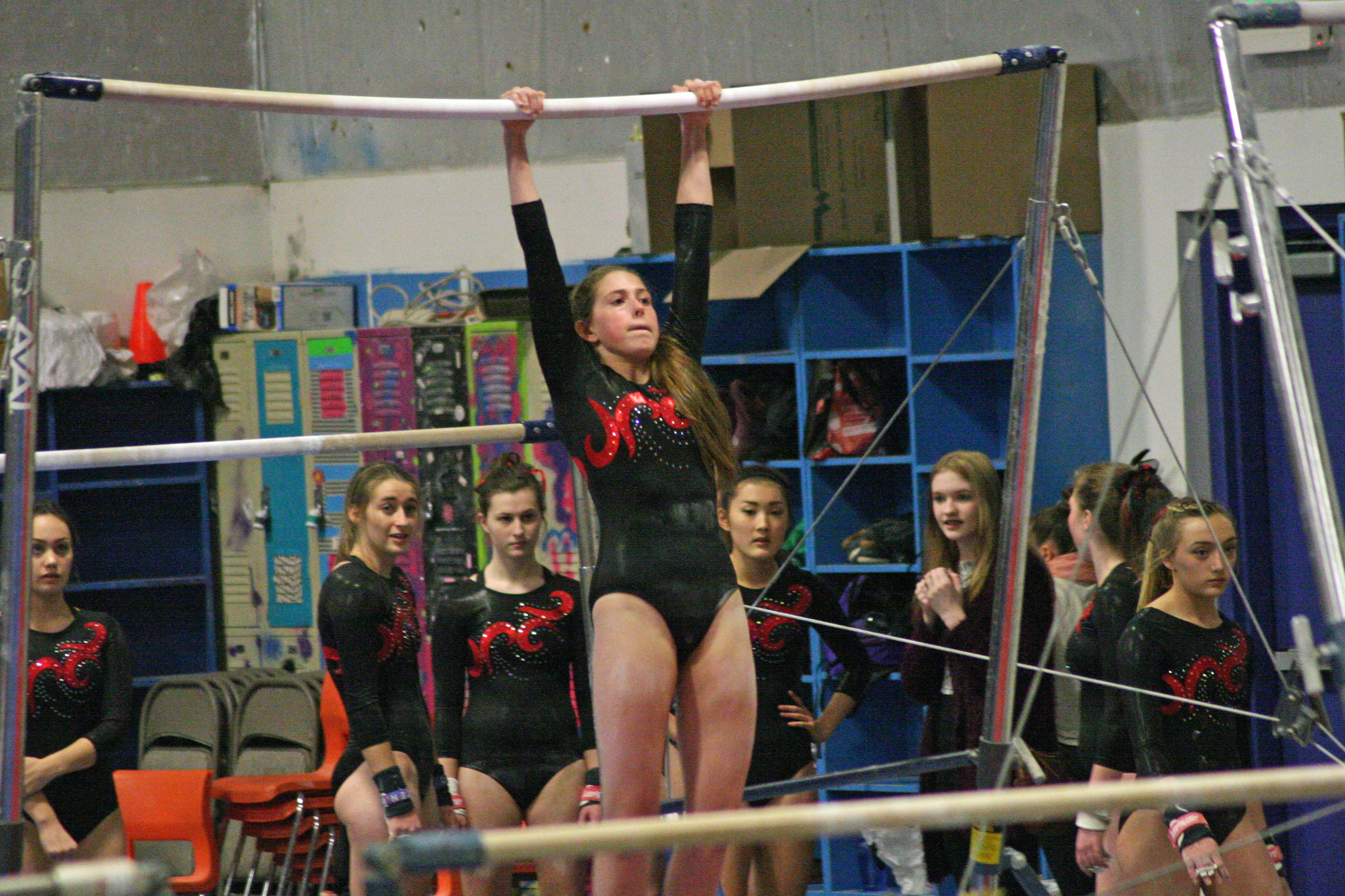 The Papermakers watch Courtney Coates swing on the bars.