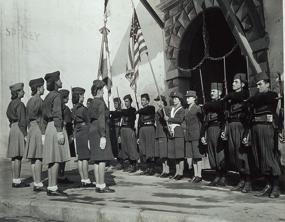 The Schlesinger Library, Radcliffe Institute, Harvard University
Flanked by soldiers of a French Zouave regiment, Dorothy (Grassby) Dwyer carries the American flag during a 1943 military ceremony at an old Northern African fortress. The women facing Dwyer are in the French army.