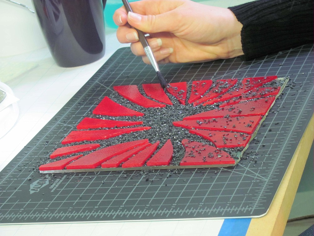 Fused glass art incorporates several different glass mediums. Here, a student uses pieces of sheet glass and frit.