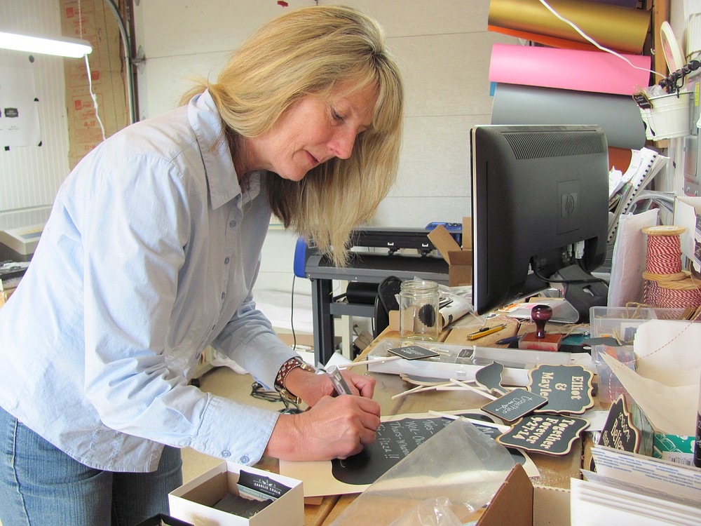 Pattie Gowing writes a menu on a chalkboard sheet created by Charlie Chalk Designs, a company she owns with two of her daughters. The home-based business also sells wine charms, Mason jar labels and wedding chalkboard stands.