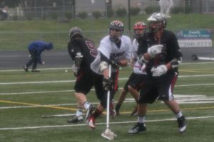Zach Quist slings the ball away from two Eastlake lacrosse players, at Doc Harris Stadium.
