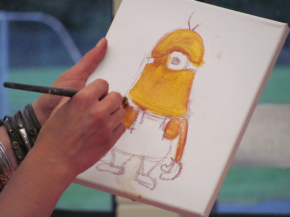 Elida Field demonstrates a painting technique in her art class.