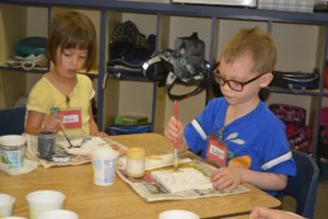 Kindergarteners Kayla Ruth (left) and Logan Jarvis apply paint to their clay tiles during the Artist in Residence program at Gause Elementary School.