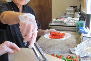 Alla Fleischer prepared sandwiches with lemon chicken and roasted red peppers, with assistance from volunteer Lynne Foster, Friday at the Camas Community Center. Fleischer, kitchen coordinator for The Meals on Wheels People Camas-Washougal, will retire at the end of this week. Cake and ice cream will be served in her honor Thursday, at the Washougal Community Center.