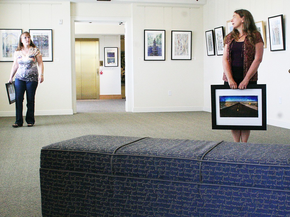 Camas Camera Club members Kirsten Muskat (right) and Sherry Brookshire discuss the upcoming exhibit in the Second Story Gallery.