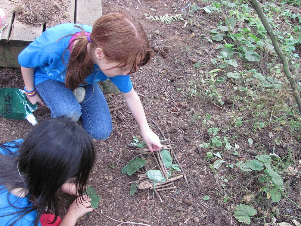 Olivia Martinez and Teagan Lafors, both 7, make a "Fairy House" from leaves, twigs and moss.