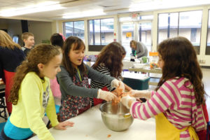Kierra Thompson, Jasmine Bergstrom, Sophie Schuett and Helena Schuett mix spicy sausage with cheese and rosemary to make cheese balls.