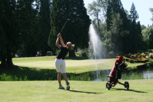Elise Filuk hits her golf ball over the water fountain and sticks it on the 16th green during the final round of districts May 10, on the Lewis River course in Woodland. 