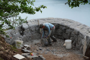 Welcome to the mason's canvas of Michael Byrne. After chiseling and hammering on his hands and knees, Byrne picks up another rock to place on the Oak View Overlook along the Cape Horn Trail.