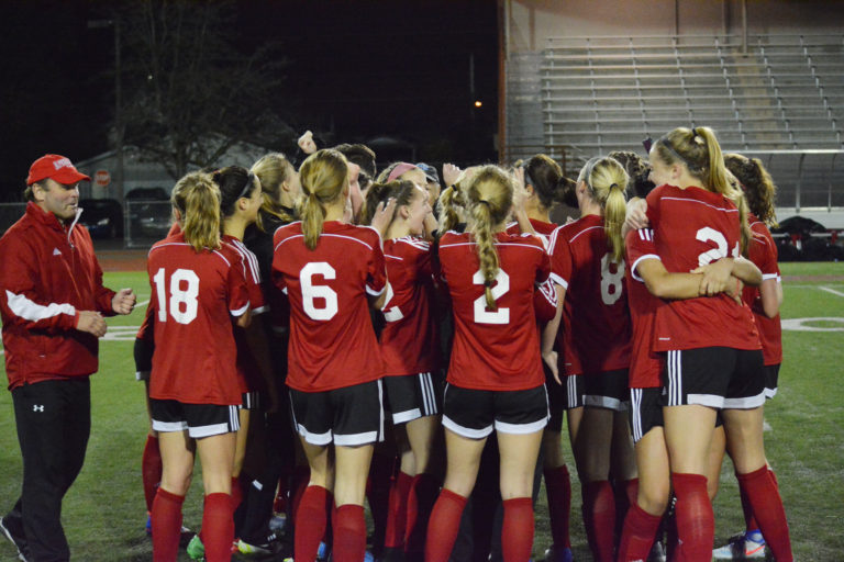 Head coach Roland Minder (left) joins the state championship celebration with the Camas High School girls soccer players.