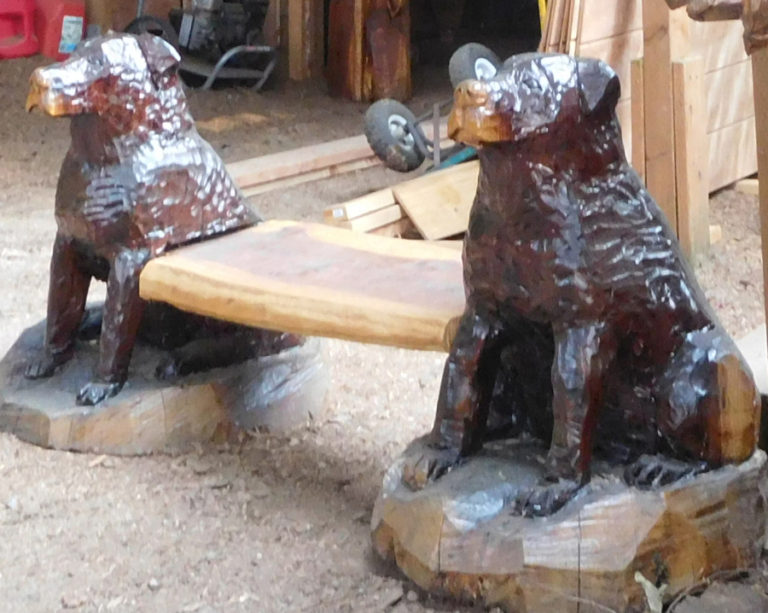 After being commisioned to create this bench, Ken Craig ended up keeping it after the client chose not to pick it up. Now, the Rotweiler bench sits beneath the shadow of a large bear carving.