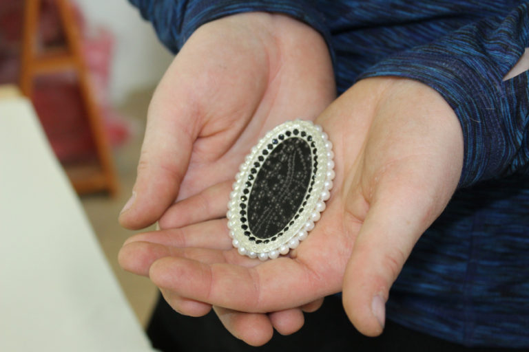 East Clark County artist Megan McGaffigan shows a visitor an example of her art jewelry.