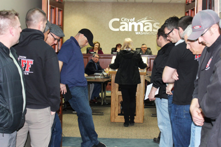 Firefighters bow their heads outside a March 19 Camas City Council meeting, while Cathy Nagode, of Camas, talks about the Feb. 14 fire that trapped her longtime boyfriend, Arthur Nichols, and the couple's dogs inside their home. Firefighters rescued Nichols and the dogs. Nichols died eight days later. Many have publicly claimed his death stemmed from smoke inhalation, but a death certificate says Nichols died from cancer and does not list the fire or smoke inhalation as a contributing factor.