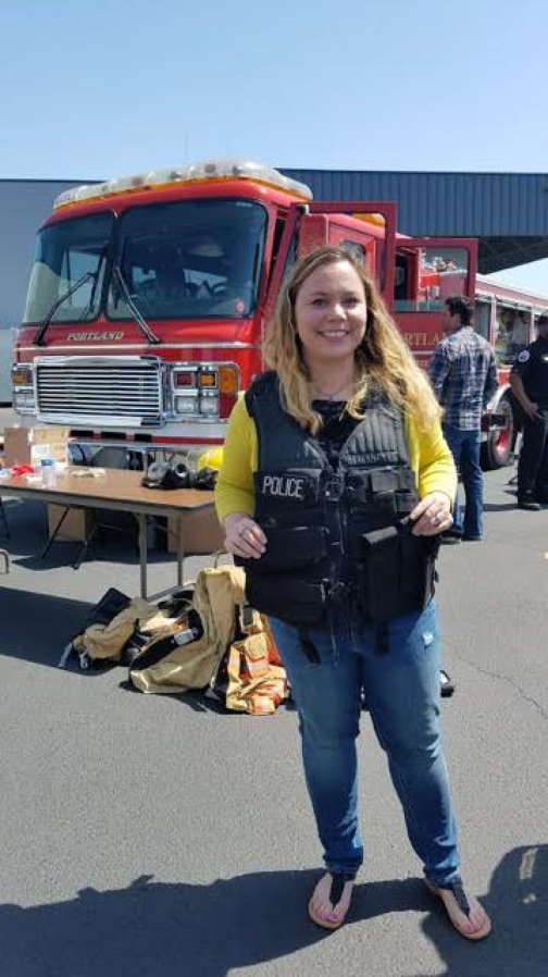 Camas High School forensic science teacher Alixandra Coker wears a police vest to feel the weight of it without the extra gear officers normally carry, during a forensics field trip to the Portland Police Bureau on April 26.