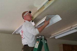 Geoffrey Ivens, a volunteer, replaces a lighting fixture at Kiwanis Camp Wa-Ri-Ki, north of Washougal. (Contributed photo by Mike Richards)