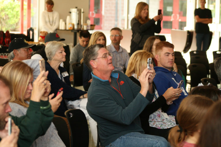 Proud parents including Brooke Roy&#039;s father Stu Roy (center) capture the signing on their phones.