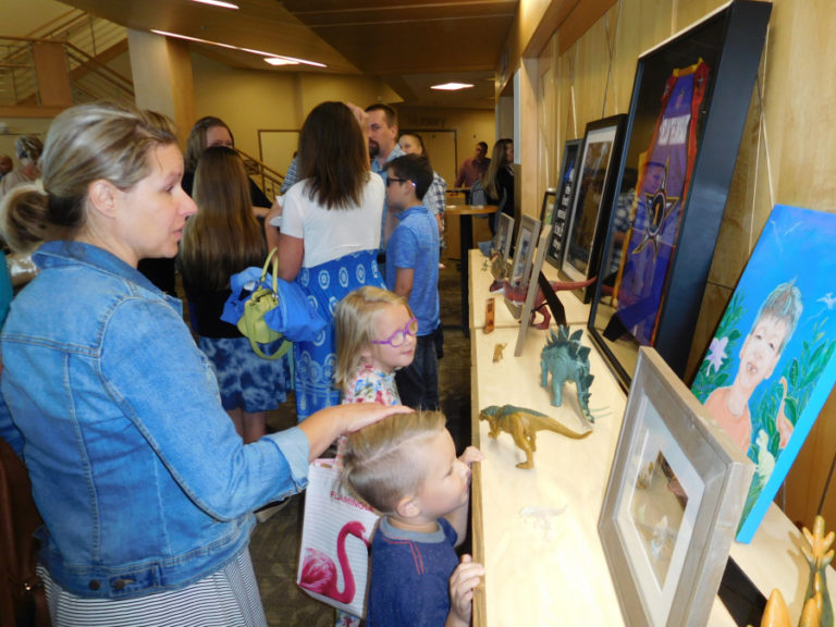 Adults and children look at photographs of and artwork depicting Declan Reagan, 6, along with dinosaur toys and a Harlem Wizards jersey, after a celebration of life service was held for Reagan, Saturday, June 9. The Harlem Wizards, a traveling basketball performing group, signed Declan and his twin brother, Adrian, to the team in April.