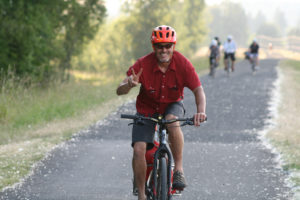 Camas Bike and Sport owner Ed Fischer pulls a trailer filled with ice and drinks to riders on the Columbia River Dike Trail, who were celebrating Fischer's bike shop's ninth anniversary. 