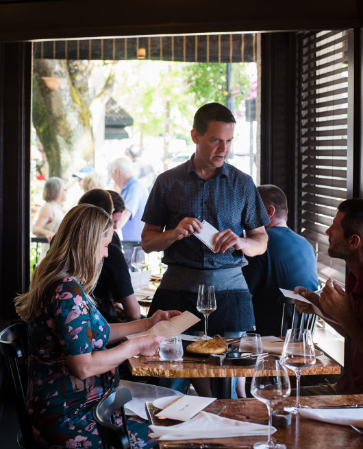 Kyle Sparks, a waiter at Hey Jack restaurant in downtown Camas, talks with customers. The new business has 12 employees.