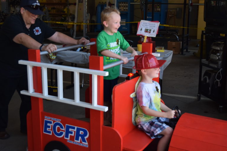 Brayden Weaver, 6, steers the wheel of the East County Fire and Rescue (ECFR) mini-engine while brother Reynold Weaver,4, enjoys the ride from the top, Sunday, July 29. The ECFR held its annual open house for the community.