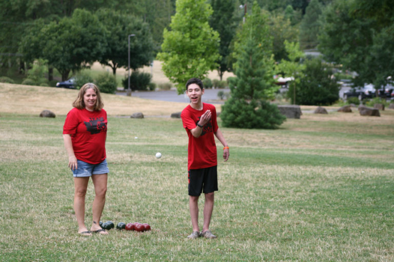 Kael Romero tosses a small white ball called a pallino.  Scoring in bocce ball is determined by how close the other balls can be rolled to the pallino.