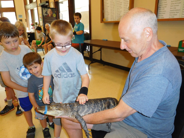 Children marvel at "Daisy," an American alligator held by Steve Lattanzi with Steve's Creature Feature, on Aug. 8, in the Washougal Community Center.