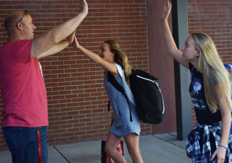 David Volke, Liberty Middle School language arts and social studies teacher, high fives students on the first day of school, Sept. 4.