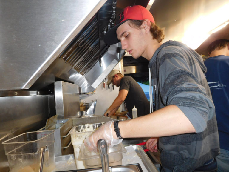 RJ Severin (left) handles some of the dinner preparation in the Coast to Coast Fresh Eats &amp; Catering food truck as chef and business owner Jess Herndon (right) cooks a variety of seafood dishes.