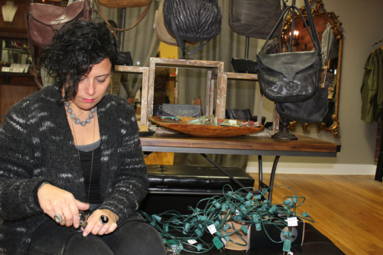 Deb Funches, an employee at Arktana, a retail boutique in downtown Camas, prepares for the holiday shopping season by swapping old lightbulbs for more energy-efficient versions.