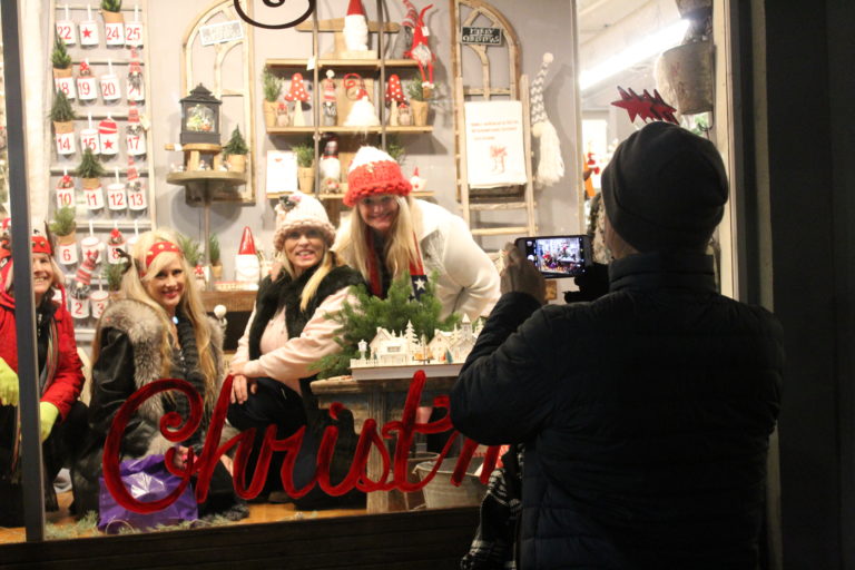 Hometown Holiday celebrants take holiday card-worthy photos inside the picture window at Camas Antiques during the 2018 Hometown Holidays celebration on Friday, Dec. 7.