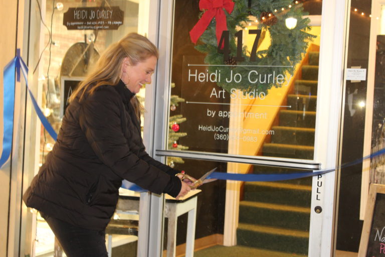 Camas artist Heidi Jo Curley cuts the ribbon at her new art studio on Northeast Fourth Avenue, above Arktana shoes, in downtown Camas, during the Friday, Dec. 7, Hometown Holidays celebration.