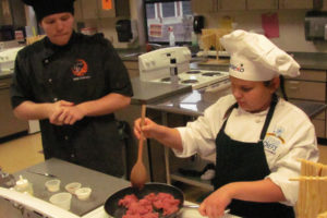 Charlotte Bisila (right), a fourth-grader at Hathaway Elementary School, prepares taco salad with Washougal High School culinary student Carter Murray assisting on March 6 during the Sodexo Future Chefs Challenge at Washougal High School. 