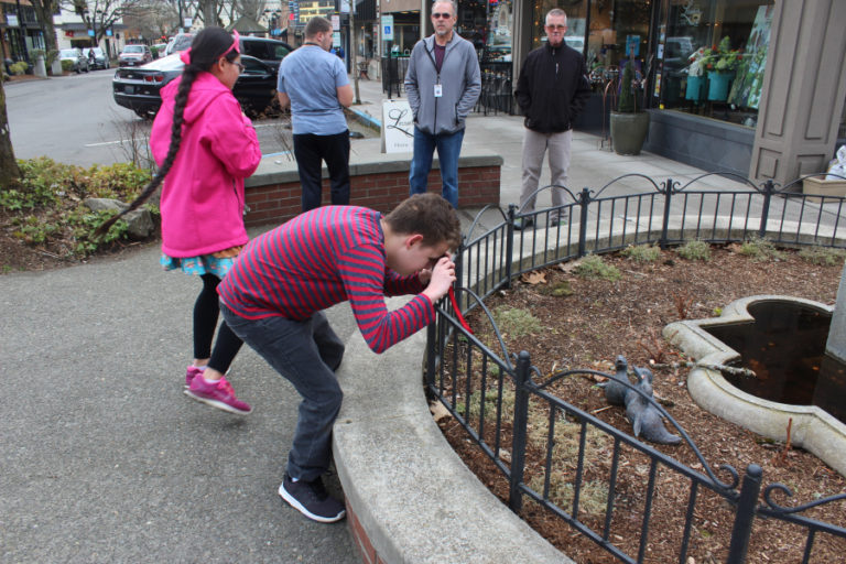 Fenix Roark, 15, an eighth-grader at the School for the Blind in Vancouver (front) takes a photo of a bird sculpture in downtown Camas on March 11, while his classmates, Inara McNew, 13 (left), and Nolan Schaffer, 17 (second from left) and their volunteer adult companions explore the corner for more photo opportunities.
