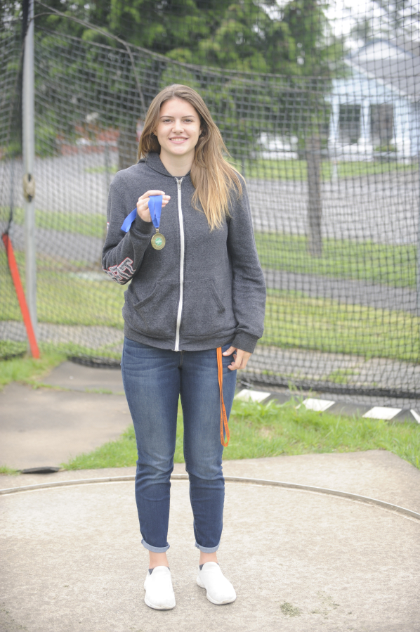 State champion discus thrower Kiersten De La Rocha holds her gold medal inside the throwing area at Washougal High School where she learned her craft.