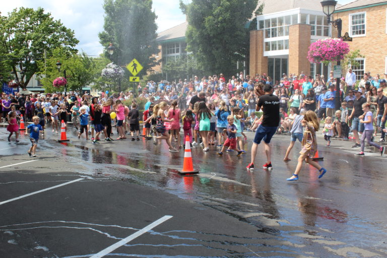 Children are "accidentally" sprayed with water from a fireman's hose between bathub races on Saturday. July 27.