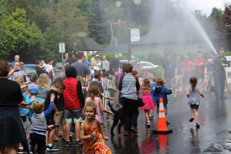 Children are "accidentally" sprayed with water from a fireman's hose between bathub races on Saturday. July 27.