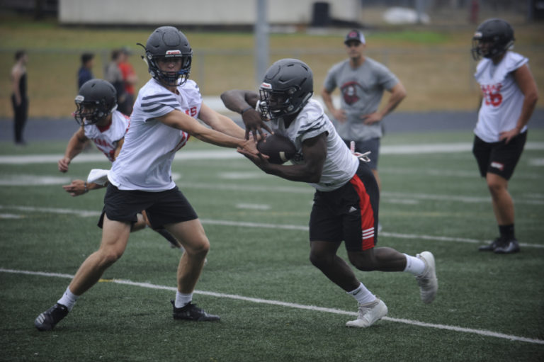 Camas High School snior running back Jacques Badaloto-Birdsell (center) takes a handoff during drills at Cardon Field at Camas High School on Aug.