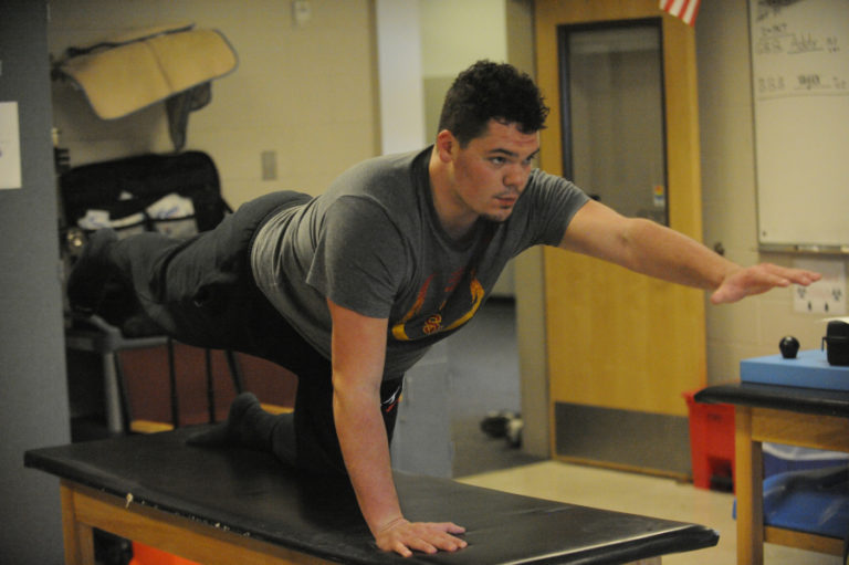 Athletic trainer Jake Howell, above, treats offensive lineman Caadyn Stephen in the Camas High School physical therapy room. Stephen is closely following a back therapy program developed by trainers at the University of Southern California.