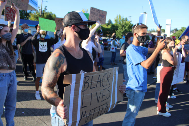 People wearing masks to help stop the spread of COVID-19 hold signs stating "Black Lives Matter" at the corner of Northeast Dallas Street and Northeast Third Avenue in downtown Camas during a counterprotest to a pro-police "Back the Blue" rally on Friday, Aug.