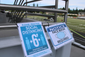 COVID-19 safety signs ask people to distance and wear face masks at the Hayes Freedom High School graduation ceremony, held June 12, 2021, at Doc Harris Stadium. (Kelly Moyer/Post-Record files)