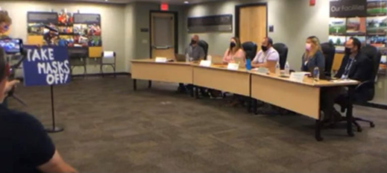 Liz Rondeau (left) the parent of three Camas High School graduates, holds a sign stating, "Take Masks Off!" while speaking to the Camas School Board on Monday, July 26, 2021.