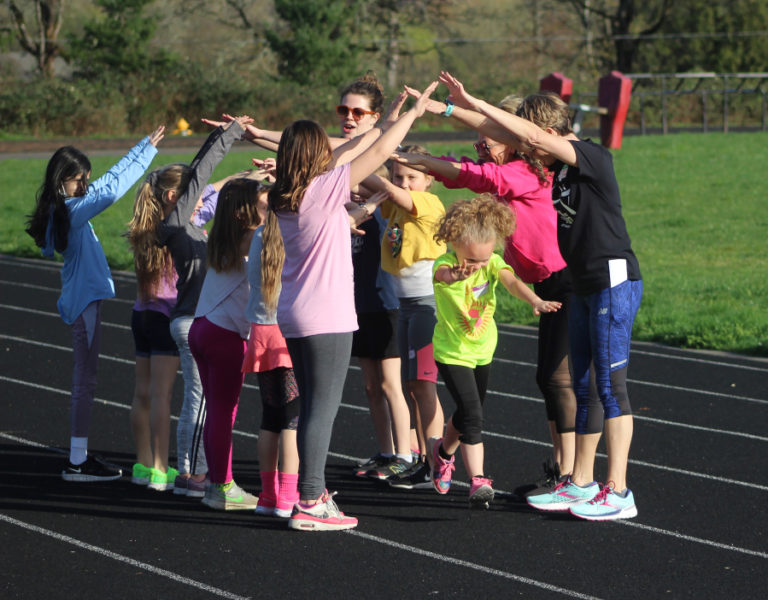 Gause Elementary School third-grade student Athena Ligons (front, center) runs through a "tunnel" of teammates and coaches during a Washougal Girls on the Run practice at Columbia River Gorge Elementary School on March 23, 2022.