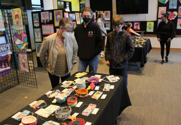 Washougal School District art teachers Dani Allen (left) and Alice Yang look at student artwork during the 2022 Washougal Youth Arts Month gallery exhibit at Washougal High School on Wednesday, March 23, 2022.