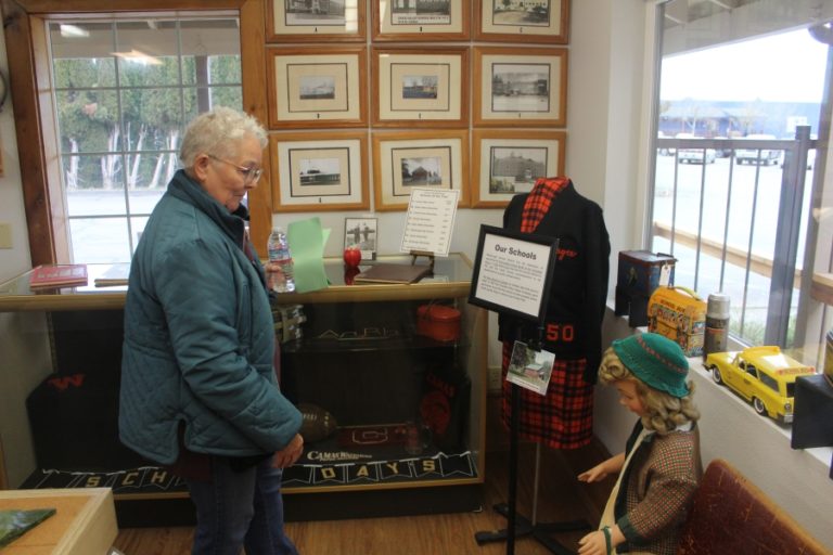 A Two Rivers Heritage Museum volunteer looks at the museum's collection of school memorabilia on Friday, Feb.