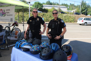 Camas Police Chief Tina Jones (left) and her officers hand out free helmets Thursday, July 27, 2023, during a grand reopening event for Camas' Riverside Bowl Skatepark. (Kelly Moyer/Post-Record files)