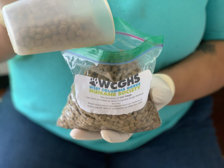 A West Columbia Gorge Humane Society staffer pours pet food bound for the Washougal shelter's food pantry.
