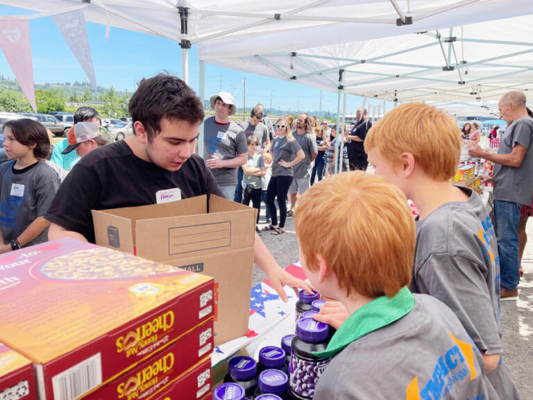 An IMPACT Camas-Washougal volunteer (left) verifies the contents of a food box in the spring of 2023.