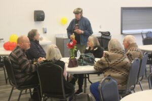 Washougal Senior Association President Charlie Walker, standing, talks with fellow older adults during a celebration event at the Washougal Community Center on Feb. 18, 2025. (Doug Flanagan/Post-Record)